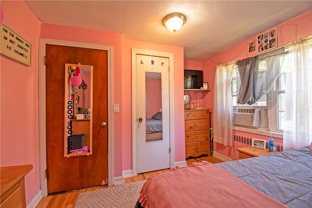 bedroom with cooling unit and light hardwood / wood-style floors