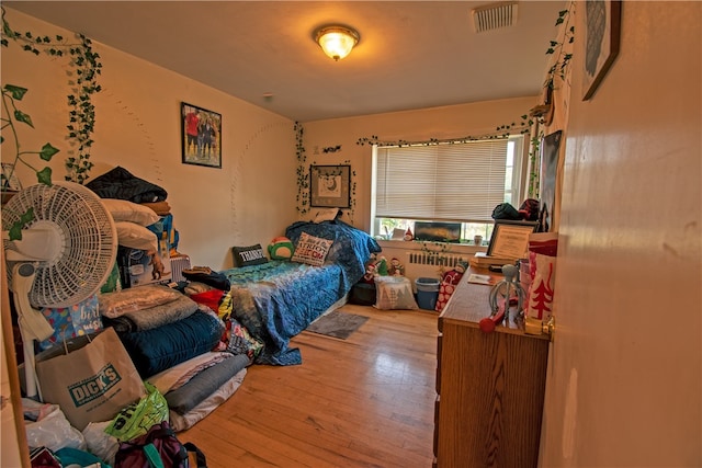 bedroom with radiator heating unit and light wood-type flooring