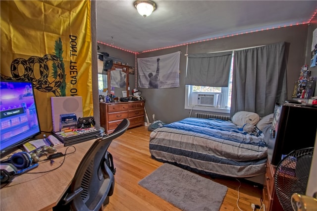 bedroom with wood-type flooring, cooling unit, and radiator heating unit