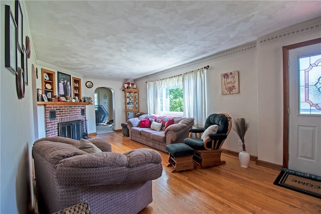 living room with ornamental molding, light hardwood / wood-style flooring, and a brick fireplace