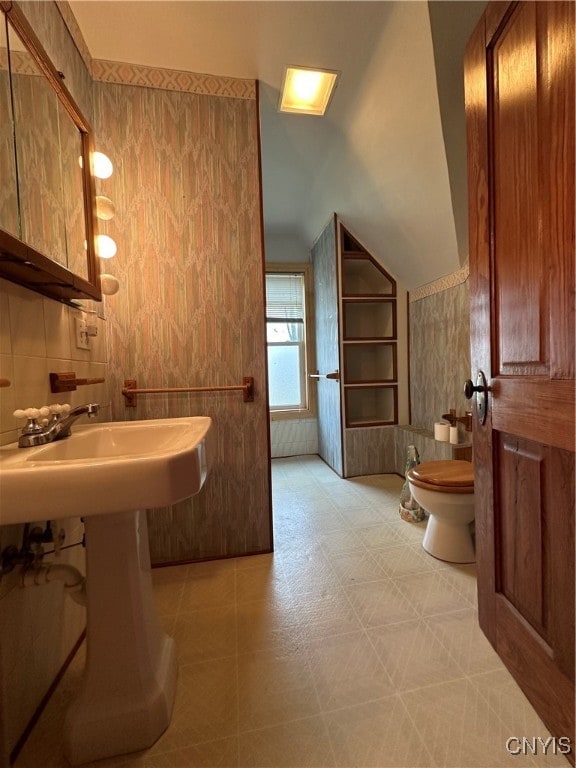 bathroom featuring toilet and tile walls