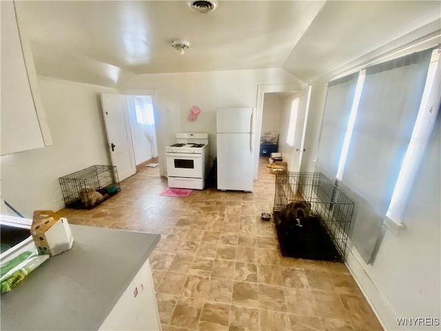 kitchen with white cabinetry, white appliances, and vaulted ceiling