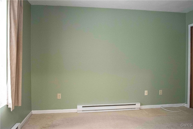 spare room with light carpet and a baseboard heating unit