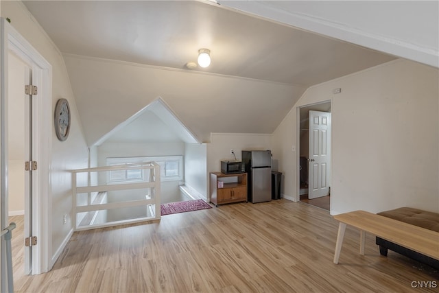 additional living space with vaulted ceiling and light hardwood / wood-style floors