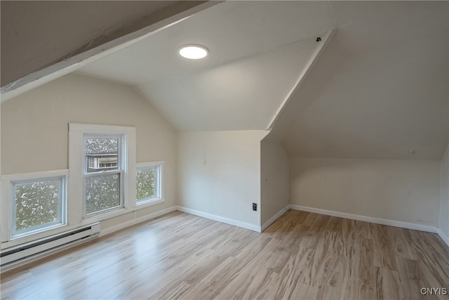 additional living space featuring lofted ceiling with beams, a baseboard heating unit, and light wood-type flooring