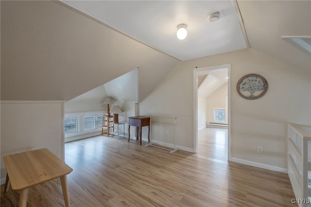 additional living space with light hardwood / wood-style floors and lofted ceiling