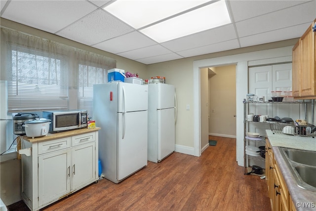 kitchen with white fridge, hardwood / wood-style flooring, a drop ceiling, and sink