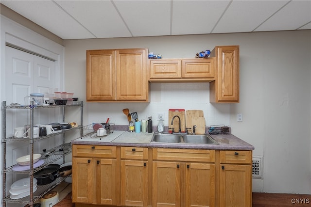 kitchen with a paneled ceiling, decorative backsplash, sink, and hardwood / wood-style floors