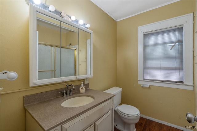 bathroom with hardwood / wood-style flooring, toilet, a shower with shower door, ornamental molding, and vanity