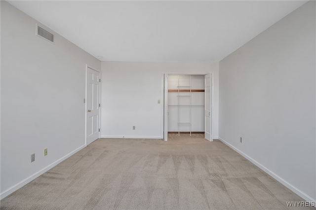 unfurnished bedroom with a closet and light colored carpet