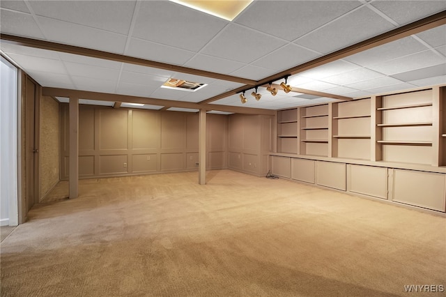 basement with a drop ceiling and light colored carpet