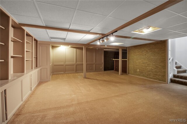 basement with a drop ceiling and light colored carpet