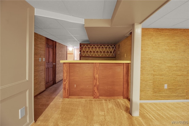 interior space featuring carpet, a drop ceiling, and wooden walls