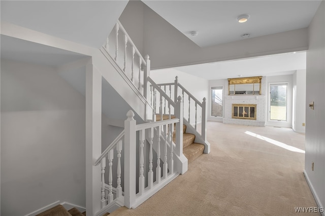 staircase with carpet and a brick fireplace