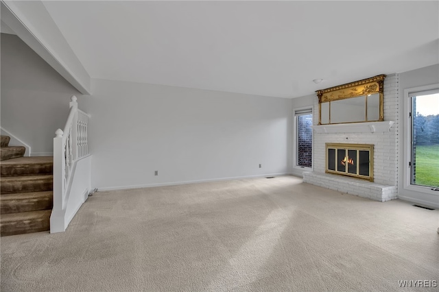 unfurnished living room with light carpet and a fireplace