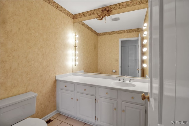 bathroom with toilet, vanity, and tile patterned flooring