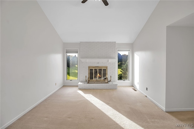 unfurnished living room with ceiling fan, vaulted ceiling, a brick fireplace, and light colored carpet