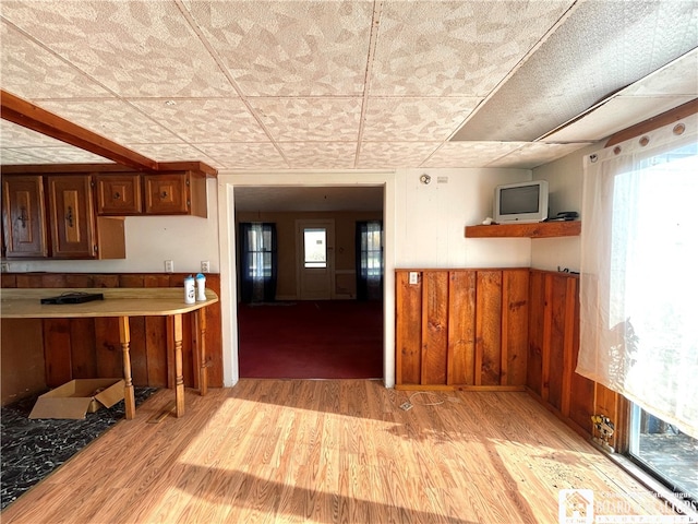 kitchen featuring light hardwood / wood-style flooring, a paneled ceiling, and wooden walls