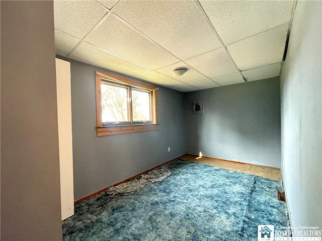 unfurnished room with a paneled ceiling and dark carpet