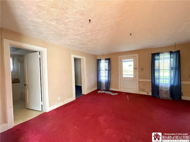 carpeted empty room with a textured ceiling