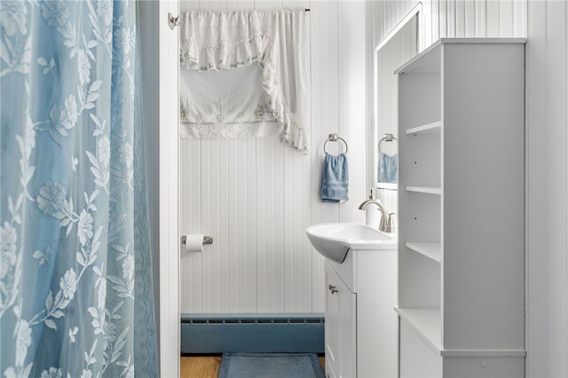 bathroom with vanity, a baseboard radiator, and wood walls