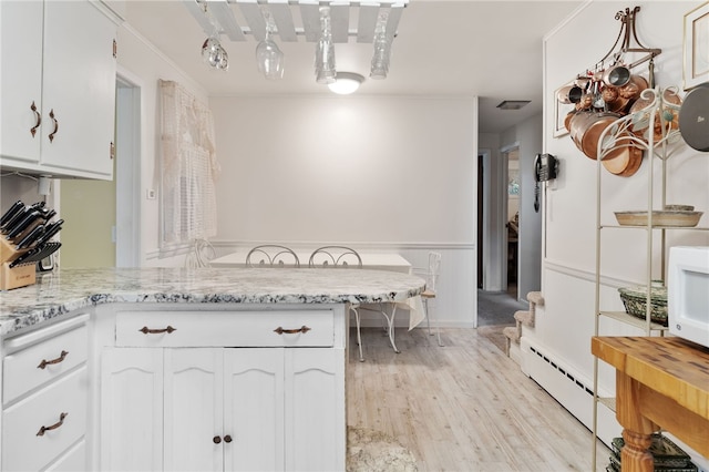 kitchen featuring kitchen peninsula, white cabinetry, light hardwood / wood-style flooring, and light stone counters