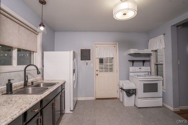 kitchen featuring light stone counters, sink, pendant lighting, and white appliances