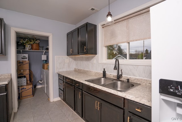 kitchen featuring light tile patterned flooring, dark brown cabinetry, sink, and pendant lighting