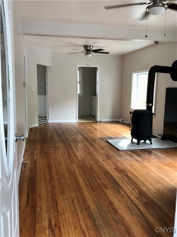 unfurnished living room with a wood stove, wood-type flooring, and ceiling fan