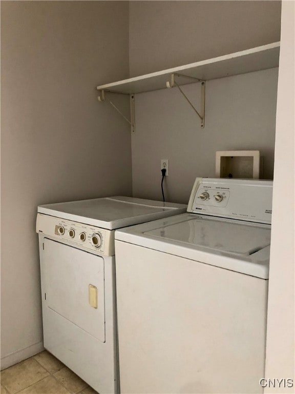 clothes washing area with light tile patterned flooring and separate washer and dryer