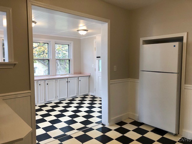 kitchen with crown molding, white cabinetry, and white fridge