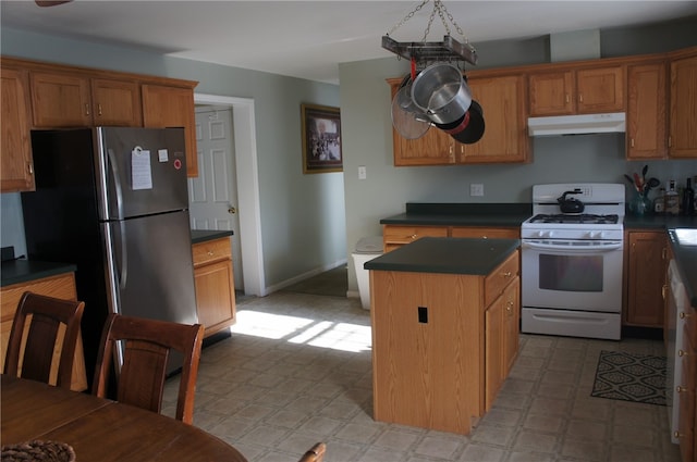 kitchen with white gas stove, a center island, and stainless steel refrigerator