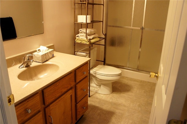 bathroom featuring a shower with door, vanity, and toilet