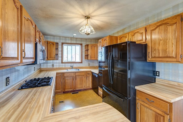 kitchen with sink, black appliances, tasteful backsplash, a chandelier, and pendant lighting