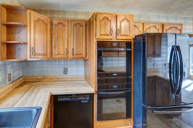 kitchen featuring black appliances, a textured ceiling, tasteful backsplash, and wood counters