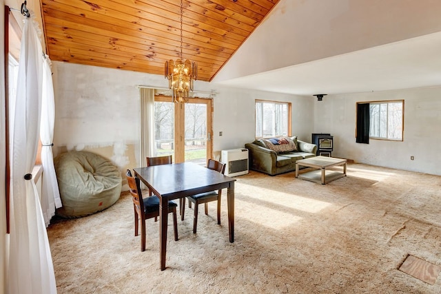 dining space with high vaulted ceiling, carpet, a wood stove, and plenty of natural light