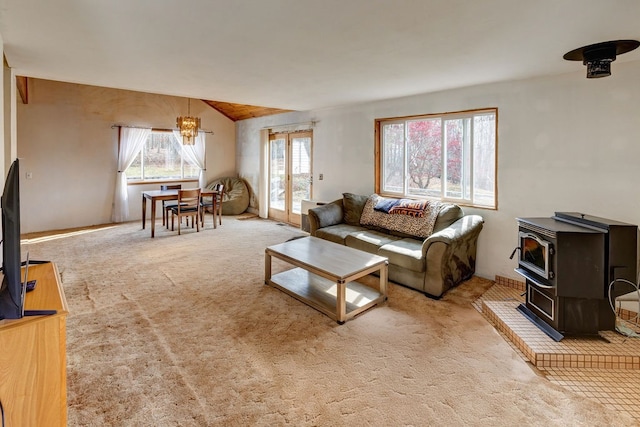 carpeted living room featuring an inviting chandelier and a wood stove