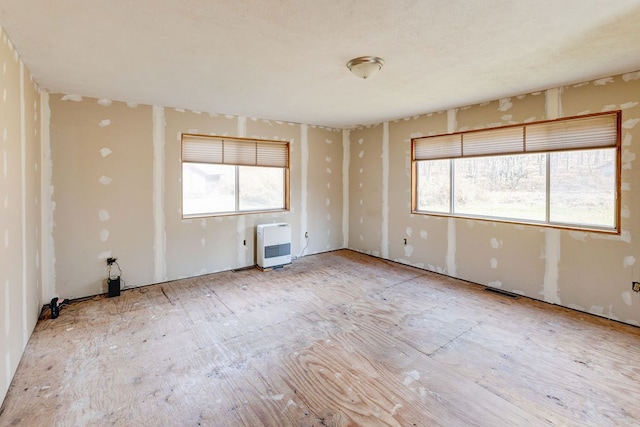 empty room featuring a healthy amount of sunlight and heating unit