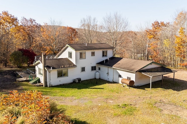 rear view of property with a lawn and central air condition unit