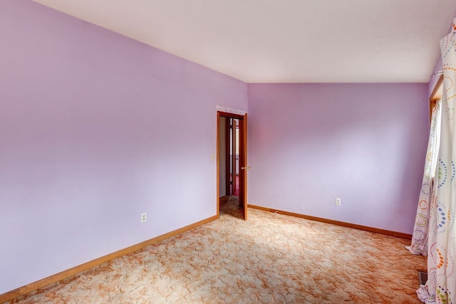 carpeted spare room featuring vaulted ceiling