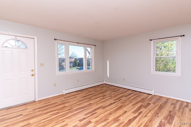 foyer entrance featuring light hardwood / wood-style floors, a baseboard heating unit, and plenty of natural light