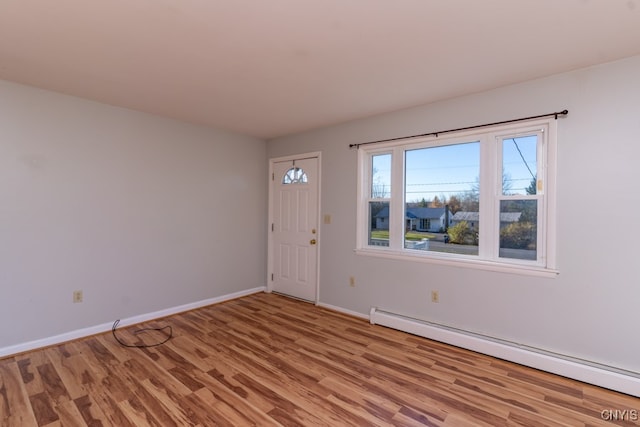 foyer entrance featuring a baseboard heating unit and light wood-type flooring