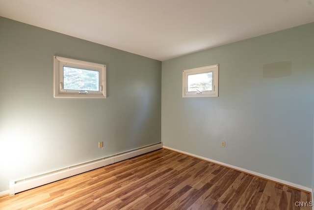 empty room featuring wood-type flooring and baseboard heating