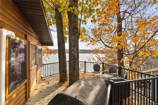 wooden terrace with an outdoor fire pit and a water view