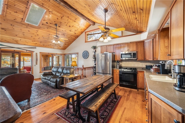 kitchen featuring sink, a skylight, light wood-type flooring, stainless steel appliances, and beam ceiling