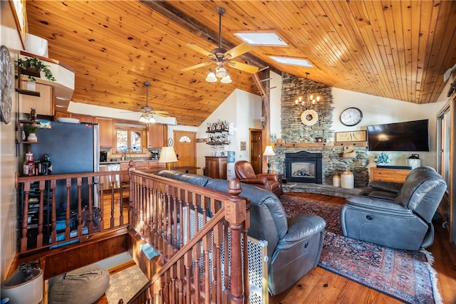 living room featuring a skylight, light wood-type flooring, a stone fireplace, wooden ceiling, and high vaulted ceiling