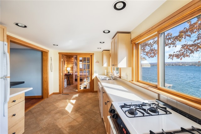 kitchen with french doors, sink, light brown cabinetry, a water view, and white appliances