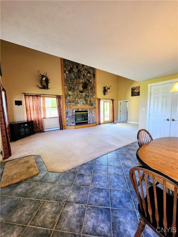 carpeted living room with a textured ceiling, a fireplace, and vaulted ceiling