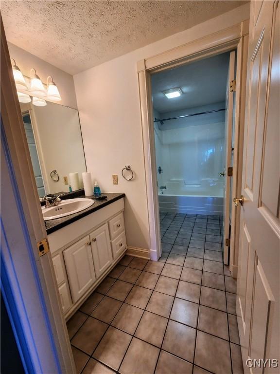 bathroom featuring washtub / shower combination, a textured ceiling, vanity, and tile patterned floors