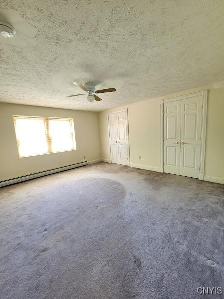 empty room with a textured ceiling, ceiling fan, light colored carpet, and a baseboard radiator